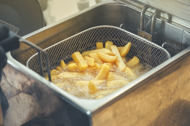 Griglia con strisce di patate abbassate in olio bollente