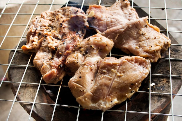 Grigliare e arrostire cibo locale carne di maiale marinato condimento stile tailandese su stufa a carbone antico vintage retrò all'aperto su Nonthaburi Thailandia