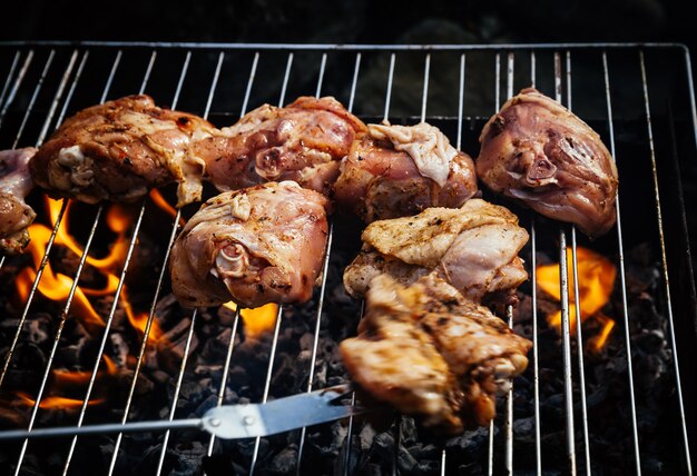 Grigliare il pollo speziato in griglia sul barbecue a carbone. Shallow DOF.