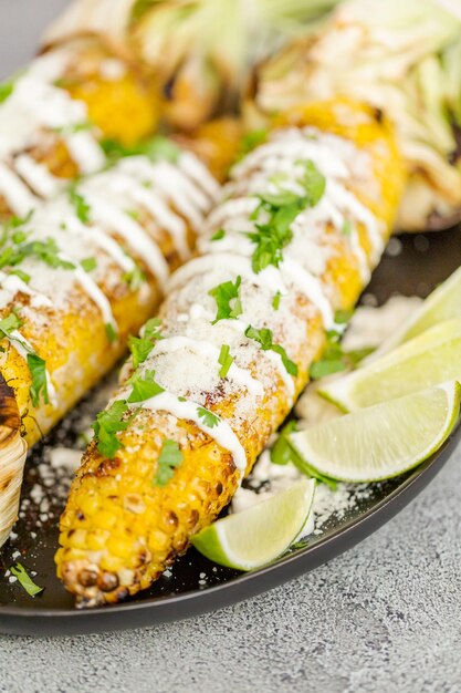 Grigliare l'elote di mais messicano guarnito con spezie e coriandolo fresco su un piatto da portata.