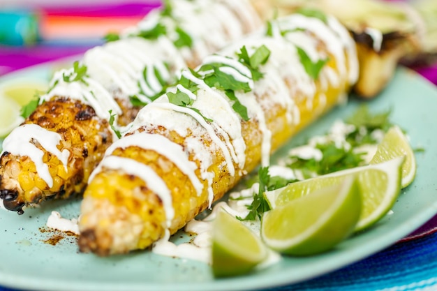 Grigliare l'elote di mais messicano guarnito con spezie e coriandolo fresco su un piatto da portata.