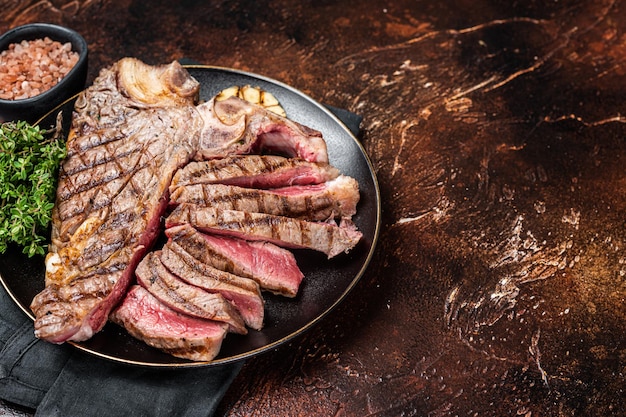 Grigliata mediamente rara Porterhouse TBone Bistecca affettata in un piatto Sfondo scuro Vista dall'alto Copia spazio