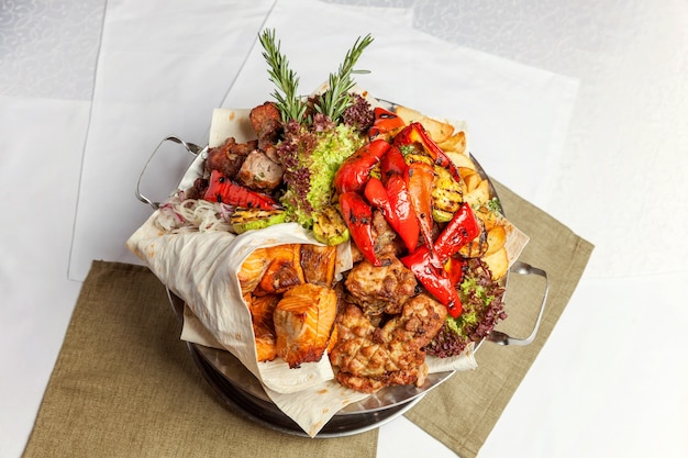 Grigliata mista di carne, verdure fritte e filetti di salmone alla griglia decorazione in piatto caldo