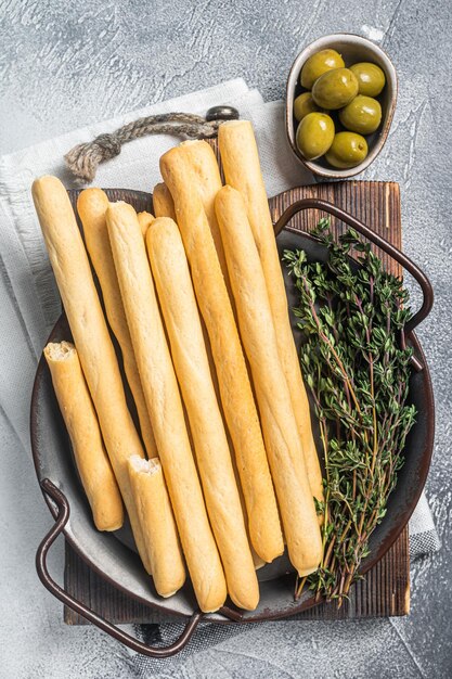 Grissini italiani in vassoio d'acciaio con erbe aromatiche Fondo bianco Vista dall'alto