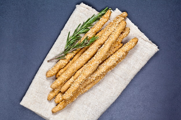 Grissini italiani o pane salato con erbe di rosmarino su tovagliolo di lino