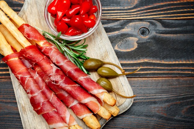 Grissini, peperoni e capperi tradizionali italiani di prosciutto crudo