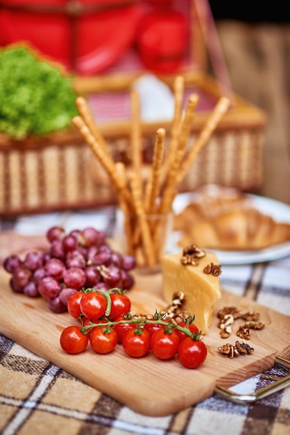 Grissini uva formaggio pomodori su tagliere di legno