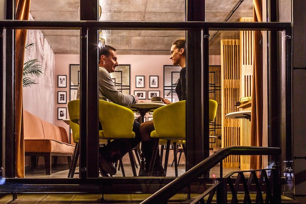 GRODNO BIELORUSSIA DICEMBRE 2018 coppia di innamorati al tavolo a bere caffè all'interno in un piccolo pub moderno con stile design loft