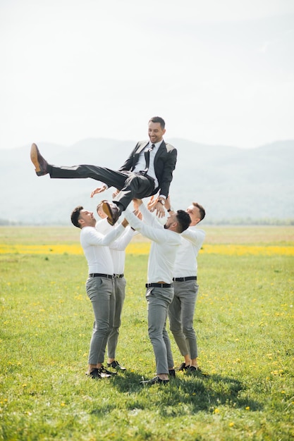 Groomsmen e sposo in posa all'aperto il giorno del matrimonio.