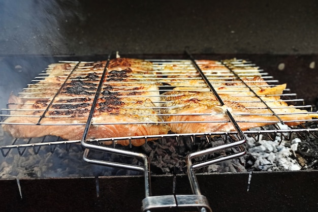 Grossi pezzi di pesce rosso vengono cotti su legno, salmone alla griglia, cibo sano e fragrante all'aperto.