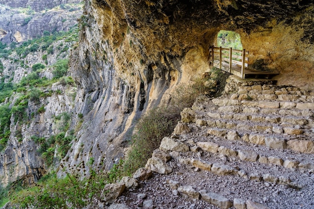 Grotta in montagna con sentiero a gradini per escursionisti.