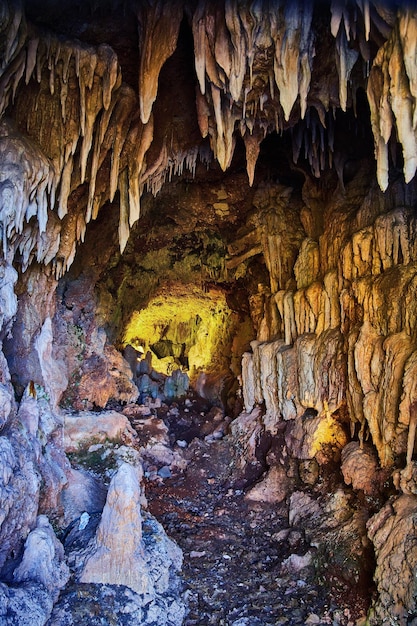 Grotta minacciosa e inquietante con stalagmiti taglienti e bagliore arancione