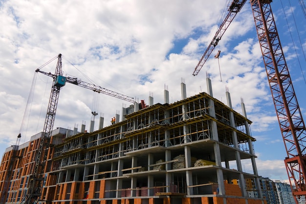 Gru a torre ad alto edificio residenziale in cemento in costruzione. Concetto di sviluppo immobiliare.