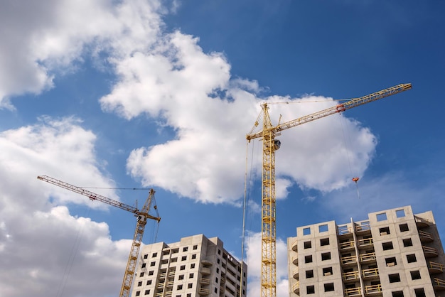 Gru a torre e alto multipiano incompiuto vicino a edifici in costruzione in una giornata di sole con belle nuvole