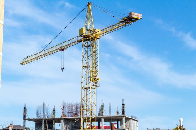 Gru a torre sullo sfondo del cielo blu in cantiere.