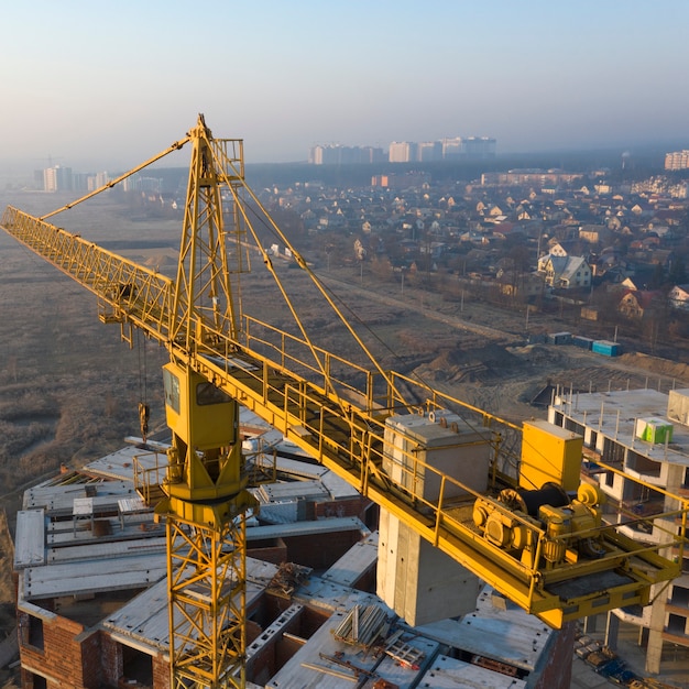 Gru da cantiere in un cantiere edile all'alba. Nebbia mattutina all'orizzonte.