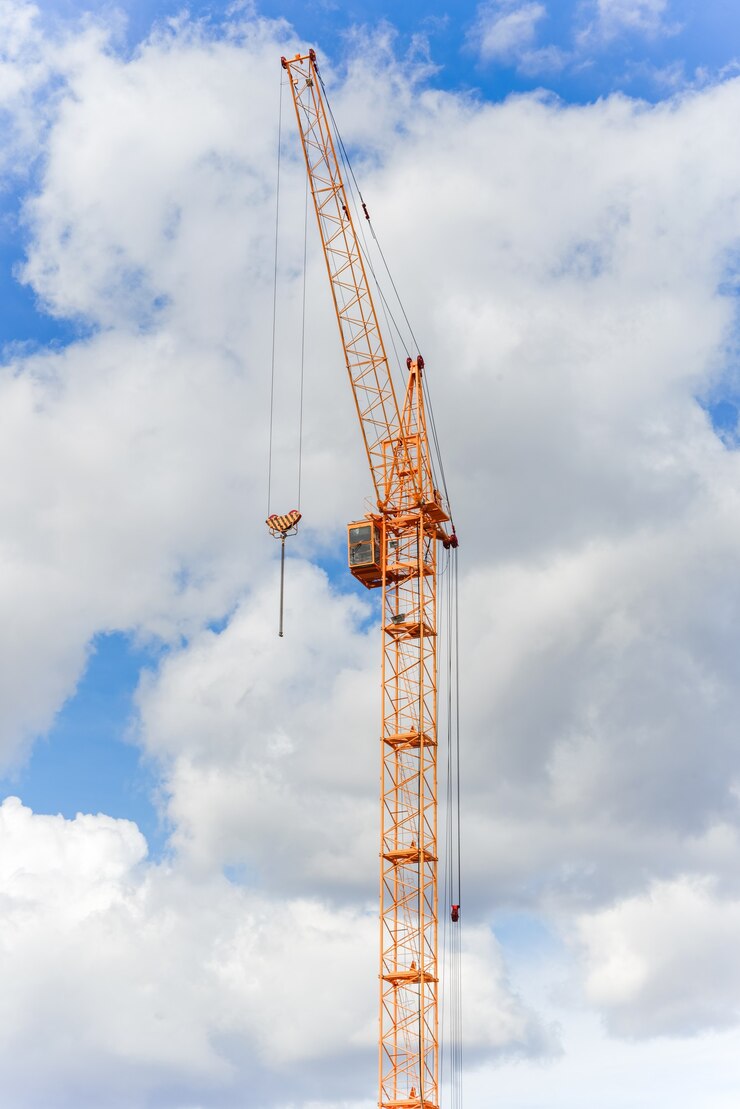 Gru da cantiere industriale contro il cielo blu con nuvole.