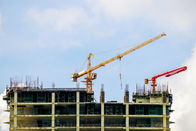 Gru di sollevamento e gru da cantiere che lavorano per la costruzione di edifici su un cielo blu brillante