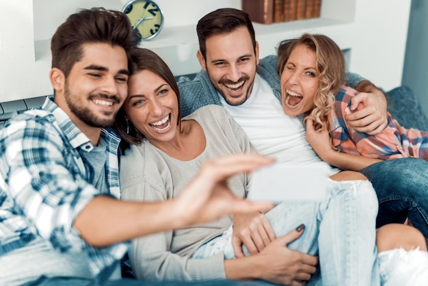 Gruppo allegro di amici che si divertono a casa, prendendo selfie.