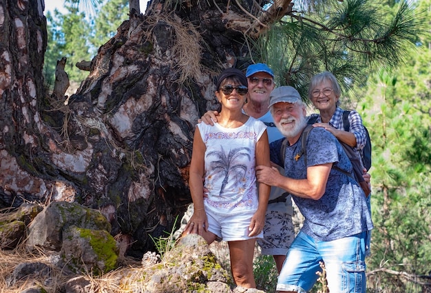 Gruppo allegro di persone anziane che guardano la macchina fotografica godendo di un'escursione in montagna nella foresta