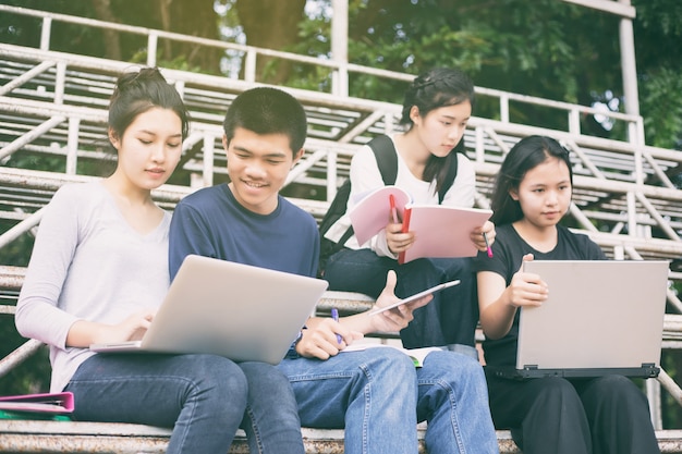 Gruppo asiatico di studenti che condividono le idee per lavorare nel prato del campus