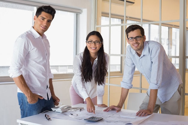 Gruppo casuale di architettura che lavora insieme sorridendo alla macchina fotografica