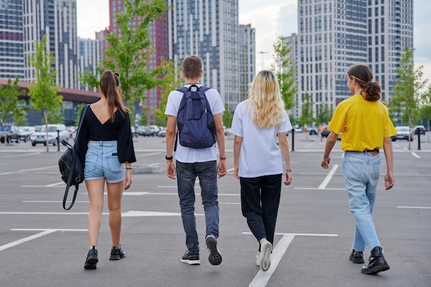 Gruppo di adolescenti che camminano insieme indietro vista sullo sfondo della città moderna in stile urbano