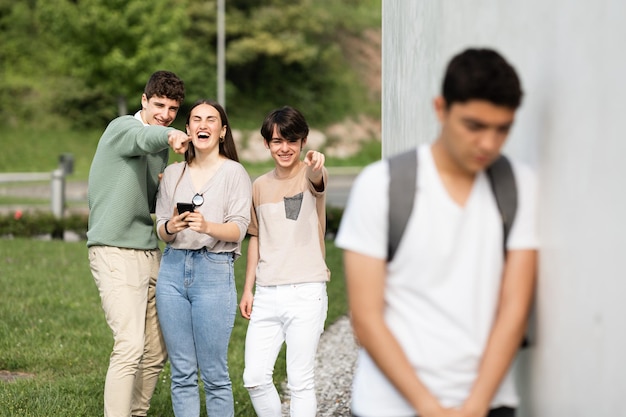 Gruppo di adolescenti che ridono del ragazzo ispanico