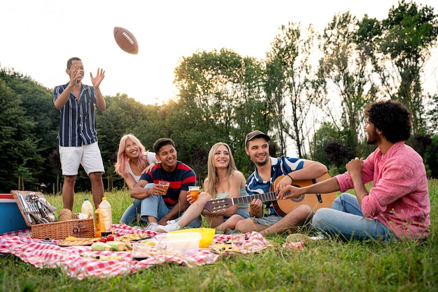 Gruppo di adolescenti multietnici che trascorrono del tempo all'aperto a fare un picnic nel parco