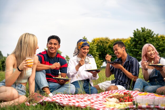 Gruppo di adolescenti multietnici che trascorrono del tempo all'aperto a fare un picnic nel parco