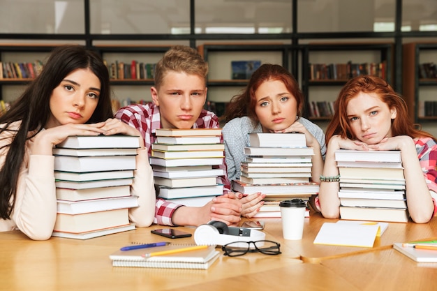 Gruppo di adolescenti stanchi seduti in biblioteca