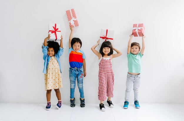 Gruppo di adorabili bambini di diverse culture che tengono scatole regalo a sorpresa in festa