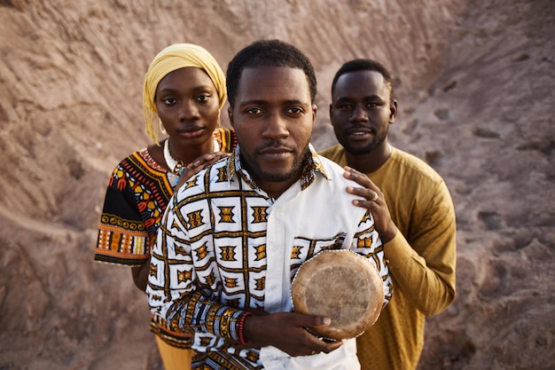 Gruppo di afroamericani in abiti tradizionali in piedi nella sabbia