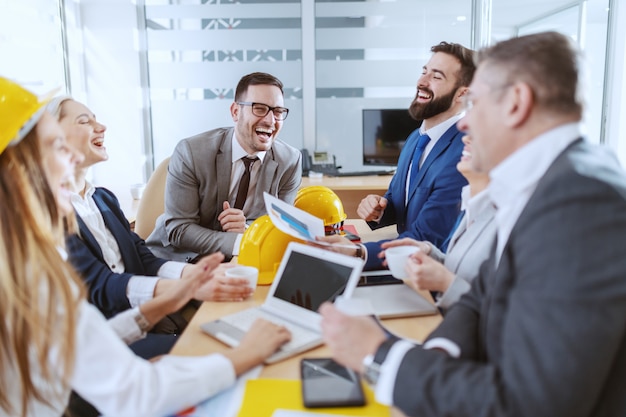 Gruppo di allegri architetti caucasici dedicati che lavorano insieme al progetto. Interno della sala riunioni.