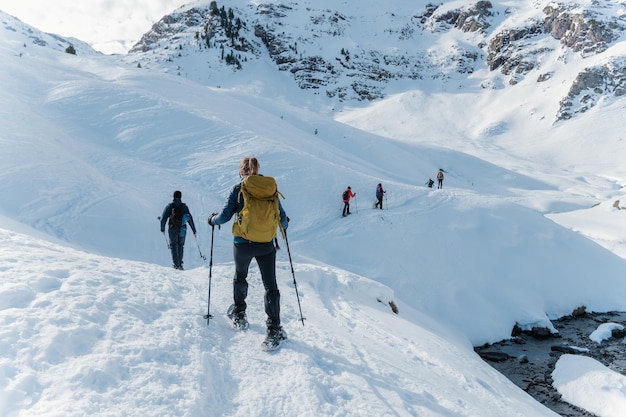 Gruppo di alpinisti che fanno un percorso con le racchette da neve in inverno in una giornata di sole nei pirenei