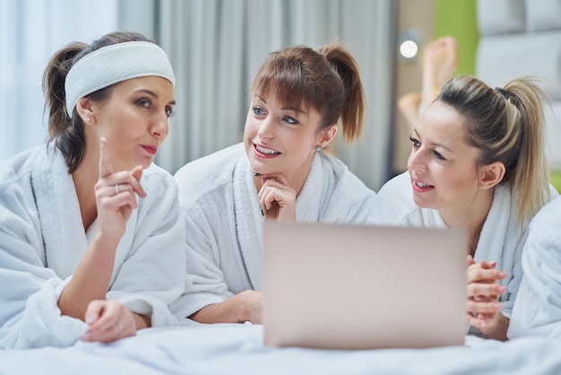 Gruppo di amiche alla festa della stazione termale dell'hotel con il computer portatile