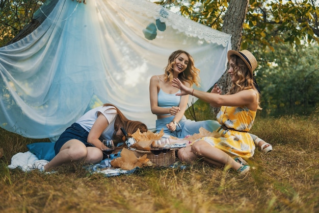 Gruppo di amiche che fanno picnic all'aperto. Loro si divertono.