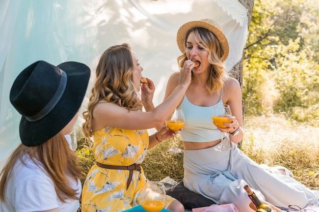 Gruppo di amiche che fanno picnic all'aperto. Si nutrono a vicenda con un croissant