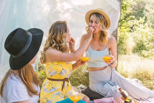 Gruppo di amiche che fanno picnic all'aperto. Si nutrono a vicenda con un croissant