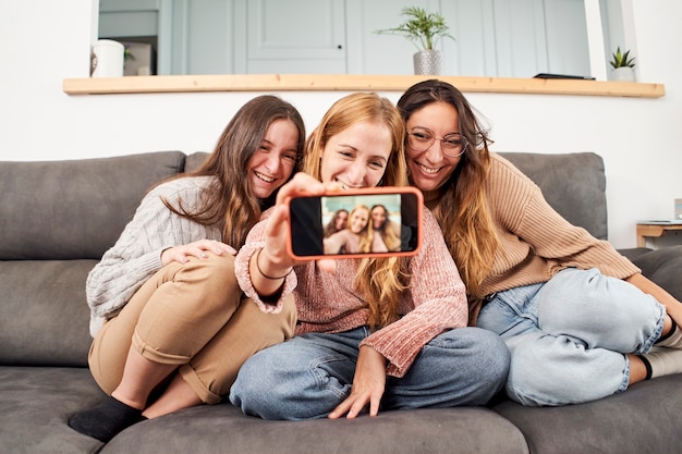 Gruppo di amiche sul divano di casa prendendo un selfie