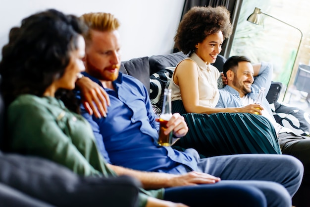 Gruppo di amici a guardare la TV, bere sidro e divertirsi