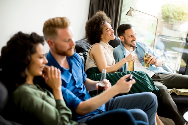 Gruppo di amici a guardare la TV, bere sidro e divertirsi