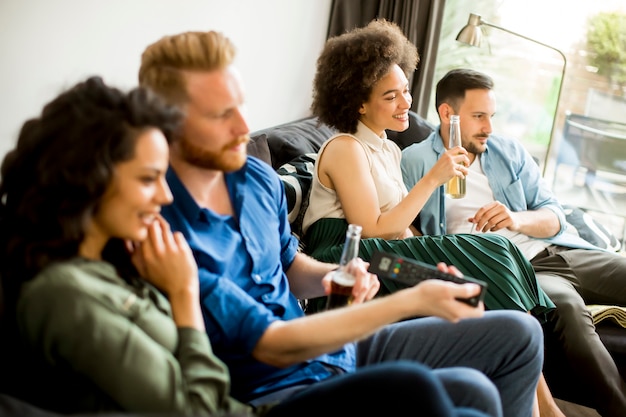 Gruppo di amici a guardare la TV, bere sidro e divertirsi