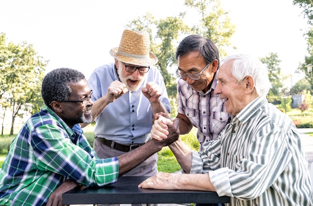 Gruppo di amici anziani che giocano a braccio di ferro al parco