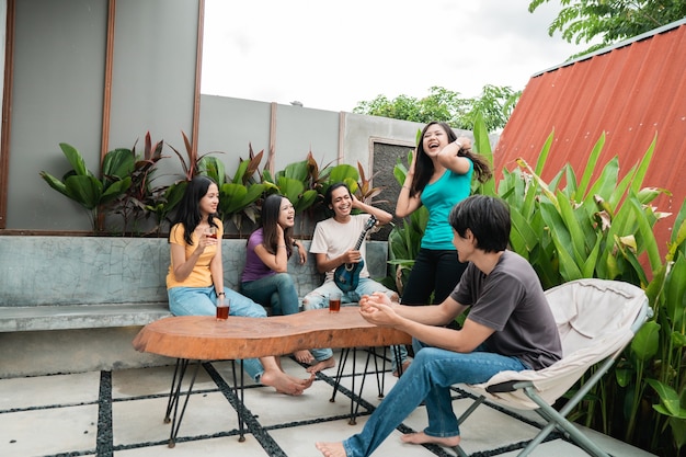 Gruppo di amici asiatici divertendosi cantando e suonando la chitarra insieme nel cortile di casa