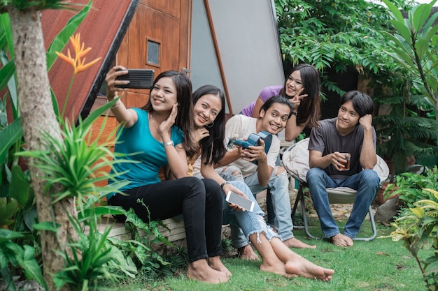 Gruppo di amici asiatici divertendosi mentre si mangia e si beve nel cortile di casa