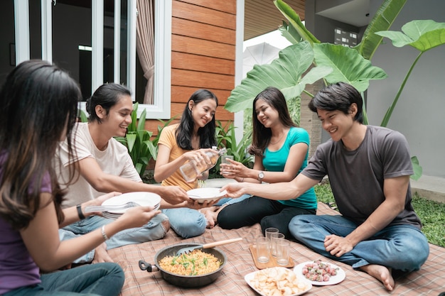 Gruppo di amici asiatici divertendosi mentre si mangia e si beve nel cortile di casa