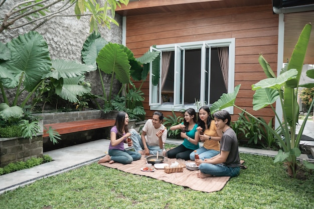 Gruppo di amici asiatici divertendosi mentre si mangia e si beve nel cortile di casa