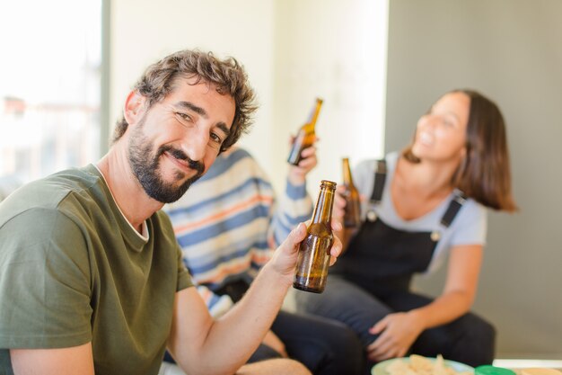 Gruppo di amici che bevono birra, rilassati e felici nella nuova casa