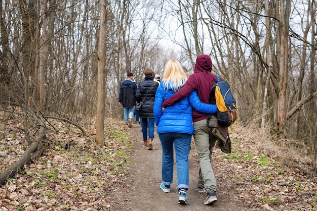 Gruppo di amici che camminano con gli zaini nella foresta di primavera dal retro